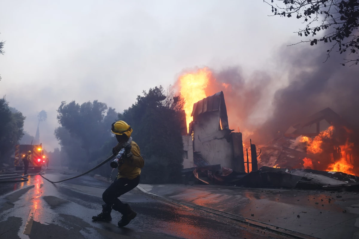 A firefighter battles the advancing Palisades Fire as it burns a structure in the Pacific Palisades neighborhood of Los Angeles on Tuesday.