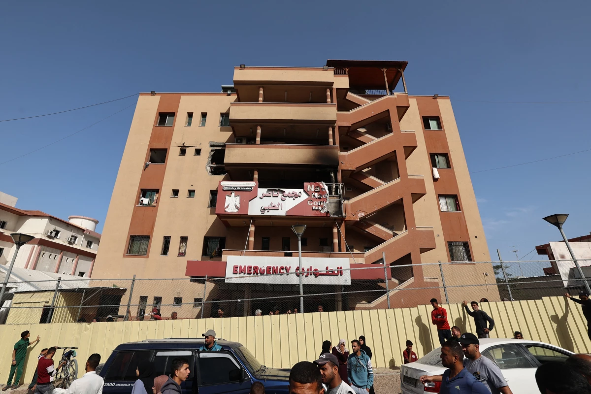 People and traffic pass the fence of the Nasser Hospital in Khan Younis, which was hit in an Israeli strike that targeted the southern Gaza Strip city at dawn on May 13.