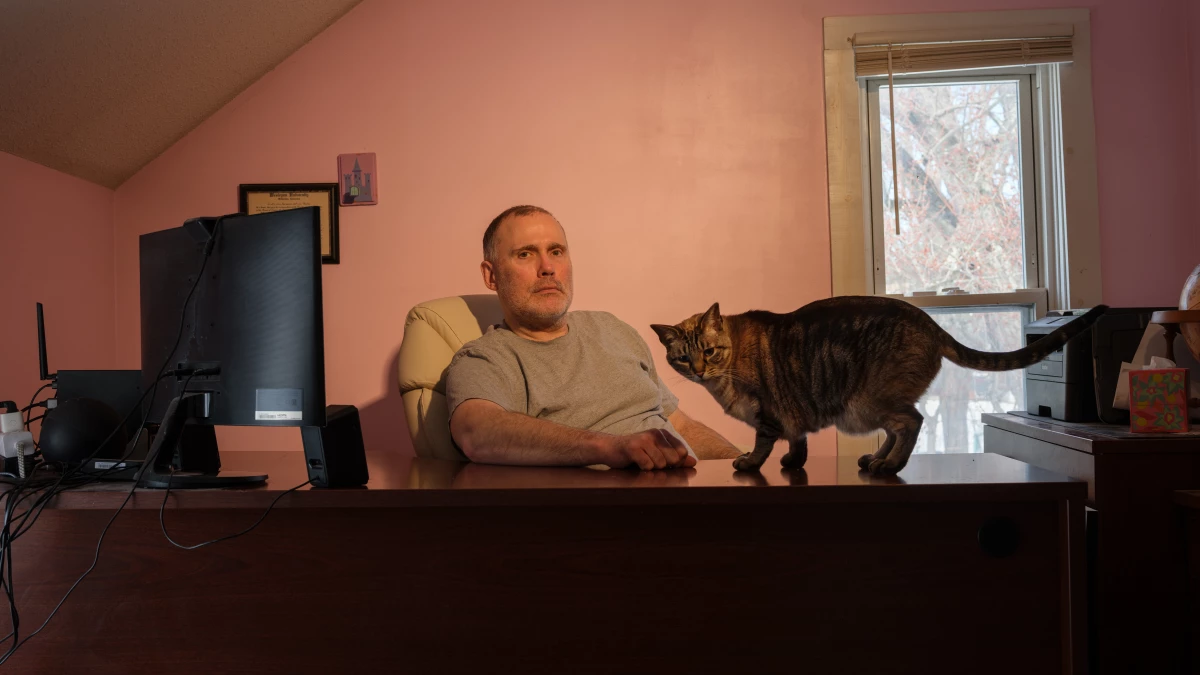 Ken Warner sits with his cat Ostara in his home office in Manchester, Conn. where he writes sci-fi and fantasy novels. Warner and his wife, Parveen Vohra, who is a therapist, buy their insurance on HealthCare.gov.