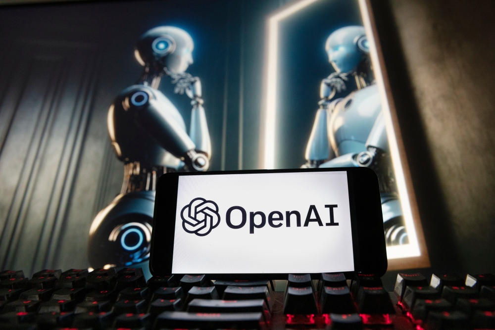 FILE - The OpenAI logo is displayed on a cellphone with an image on a computer monitor generated by ChatGPT's Dall-E text-to-image model, Dec. 8, 2023, in Boston. (AP)