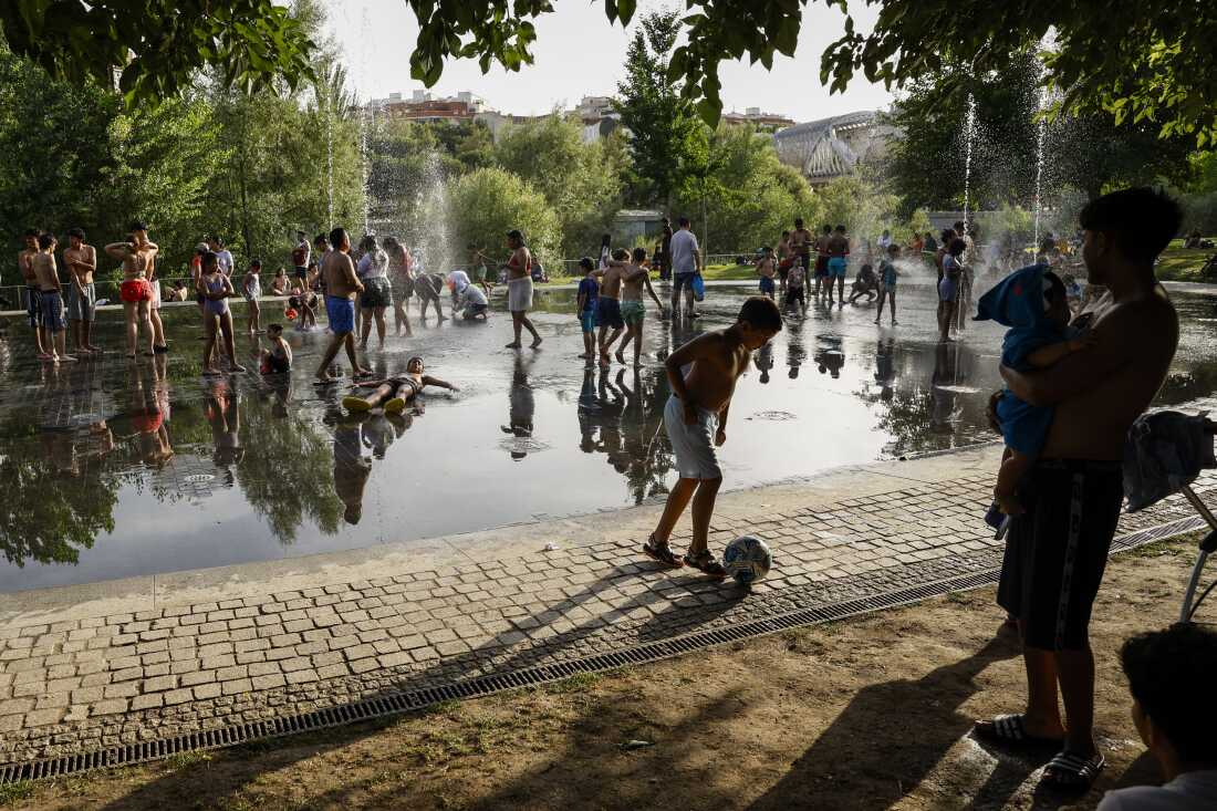 Children cool off as they play football under a fountain next to the Manzanares river on June 23, 2026 in Madrid, Spain.
