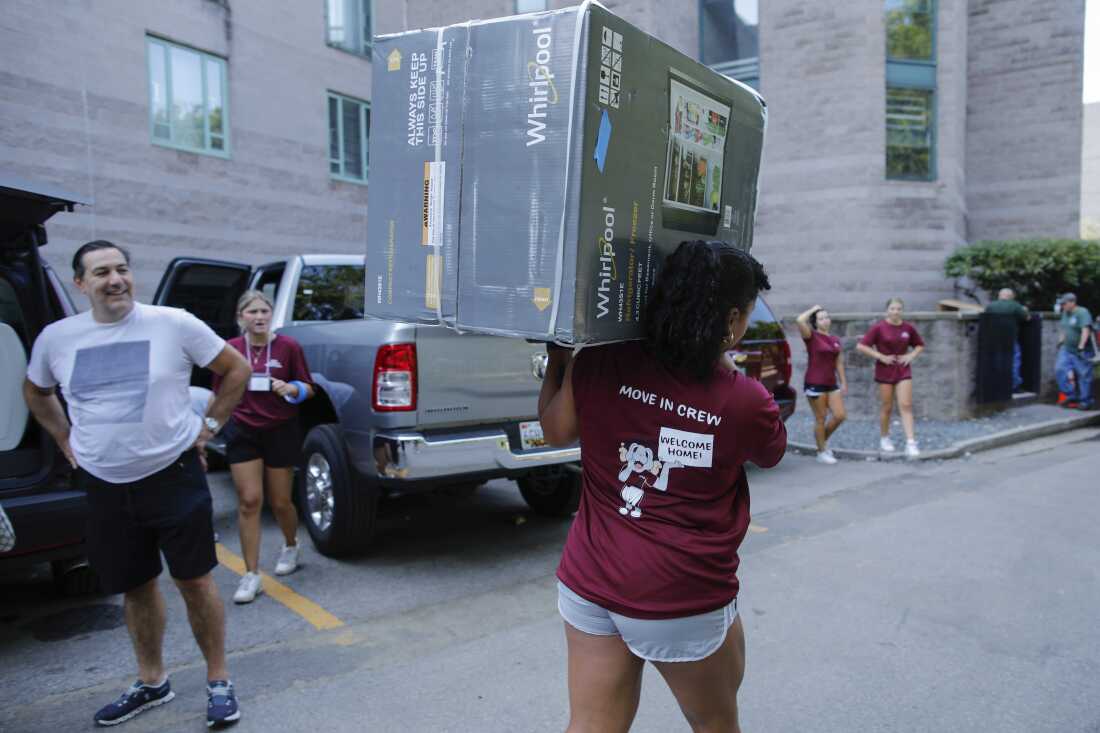 A student carries a refrigerator as new students arrive during move in day at the Fordham University Bronx campus, Aug. 25, 2024, in New York.