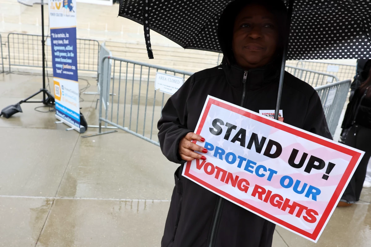 A demonstrator holds an umbrella and a sign saying 'STAND UP! PROTECT OUR VOTING RIGHTS' outside the U.S. Supreme Court in March in Washington, D.C.