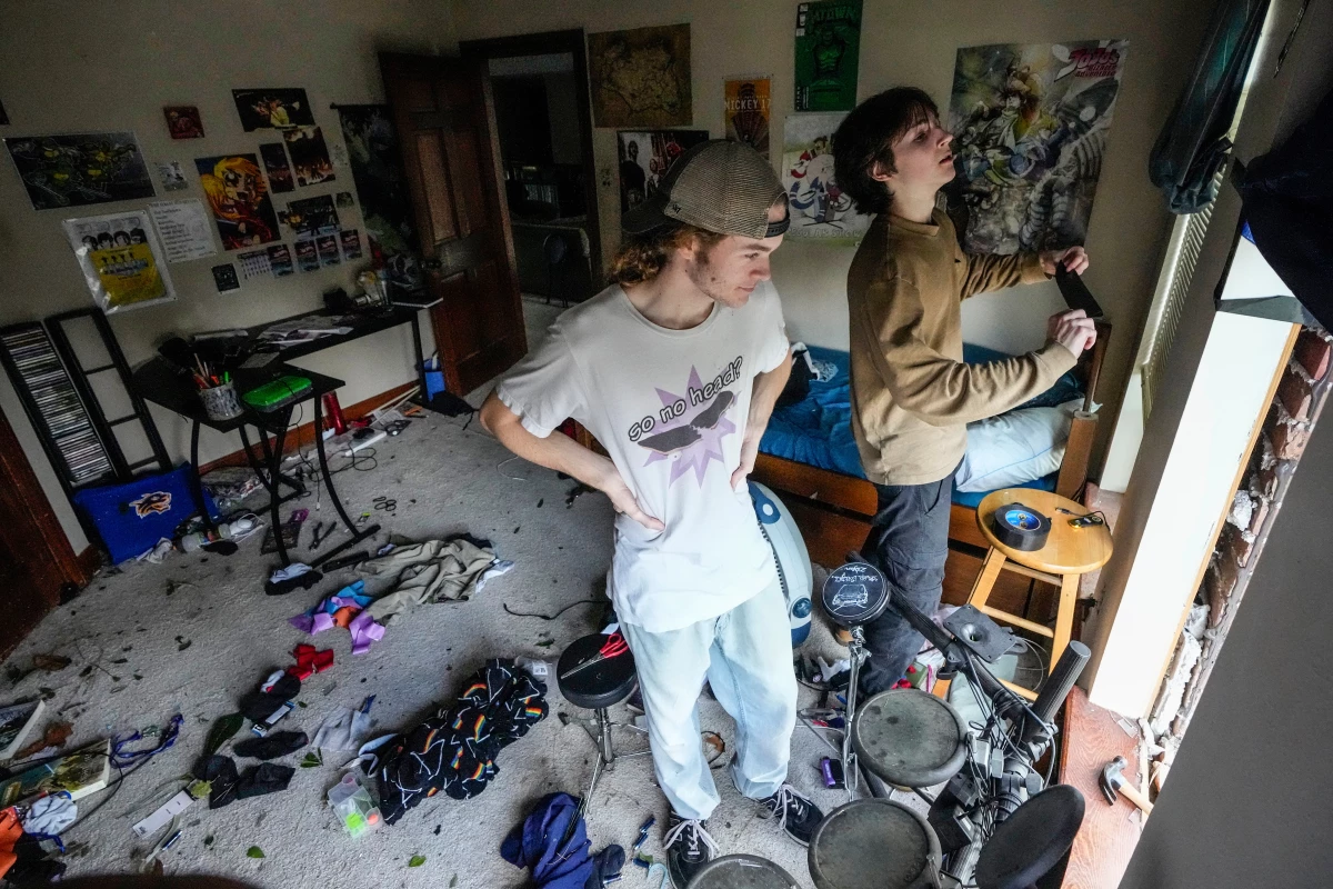 Quinn Ocker (left) and Aidan Bartlow work on installing a tarp over a blown out window in Ocker's bedroom after severe weather hit in the Memorial Northwest subdivision, in Spring, Texas, on Monday.