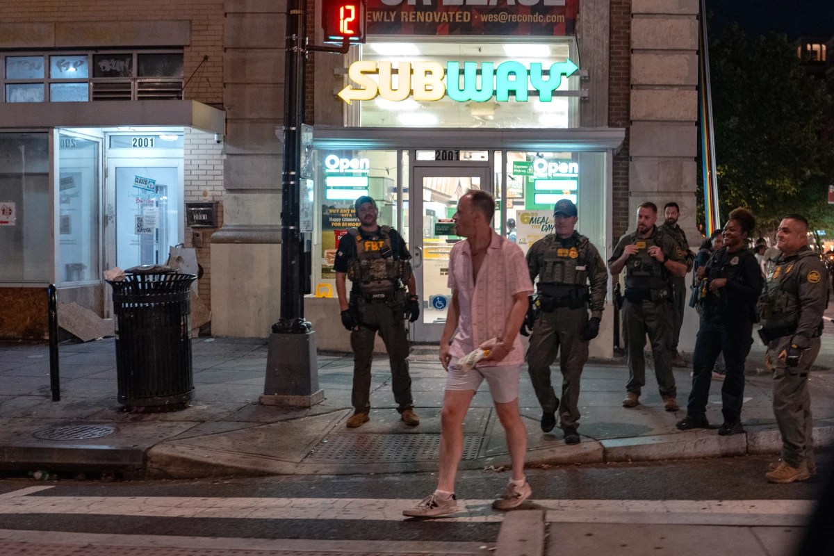 FBI and Border Patrol officers speak with Sean Charles Dunn, after he threw his sandwich at an officer, along the U Street corridor during a federal law enforcement deployment to the nation's capital on August 10, 2025 in Washington, D.C.