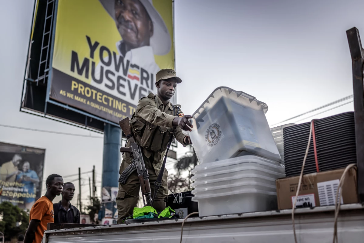 A Ugandan police officer unloads ballot boxes from a truck at a polling station set up in front of an electoral billboard supporting Uganda's incumbent president Yoweri Museveni in Kampala on Jan. 15, 2026.