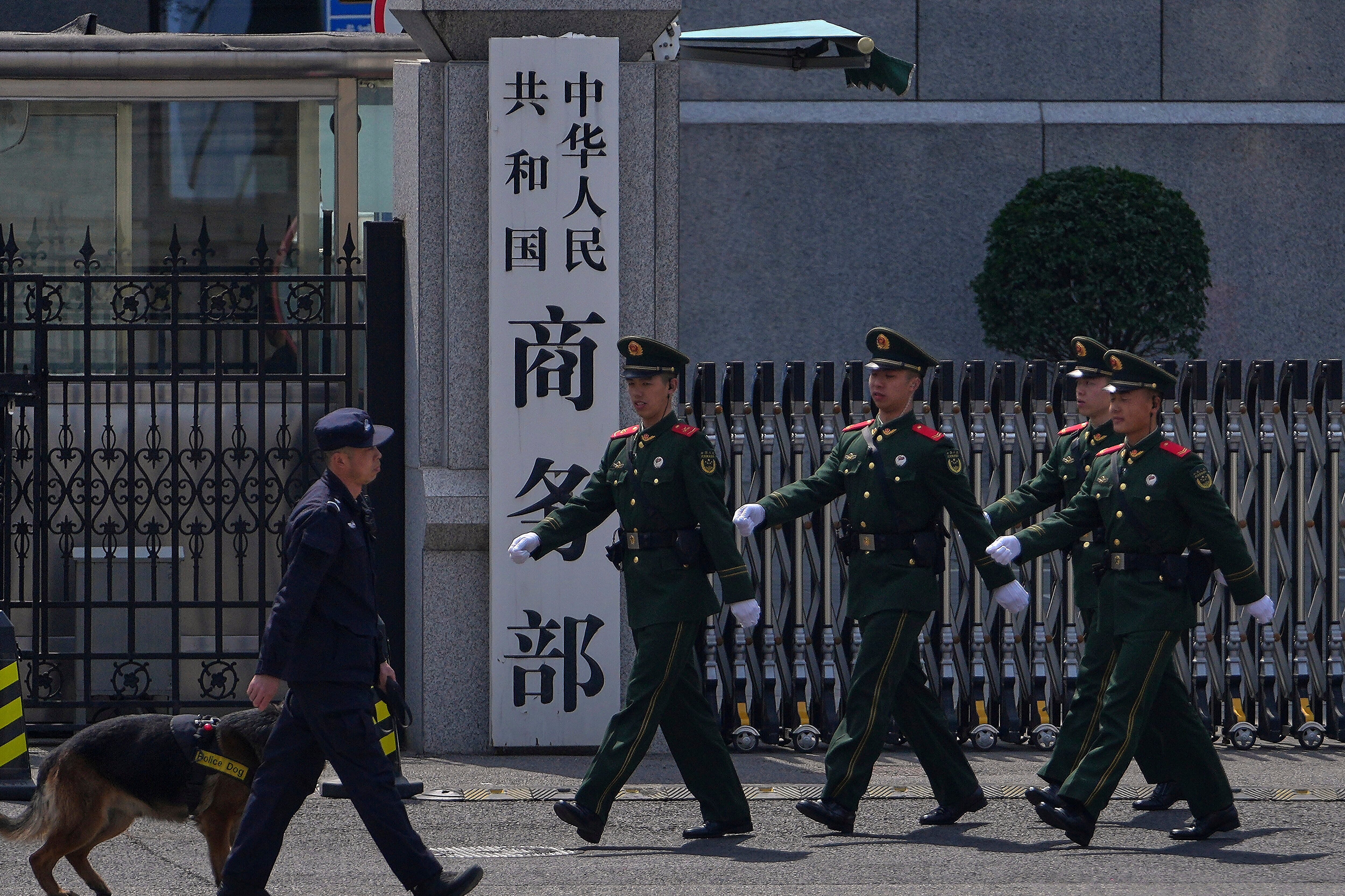 FILE - Paramilitary soldiers and a police officer with a sniffer dog march past the main entrance gate of China