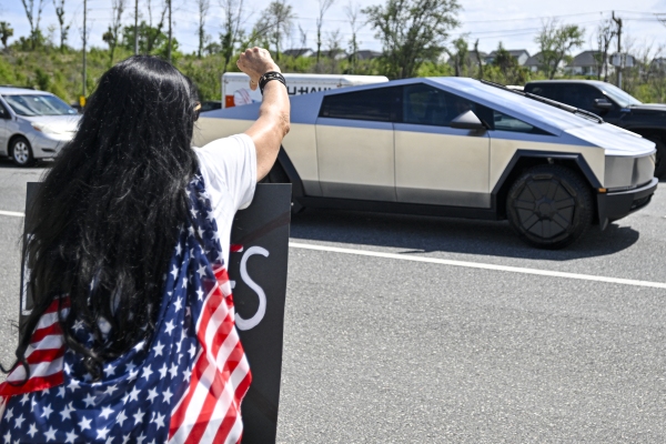 A Tesla cybertruck drives by as demonstrators rally against Tesla CEO Elon Musk outside a Tesla Store in Clermont, Fla., on Saturday.