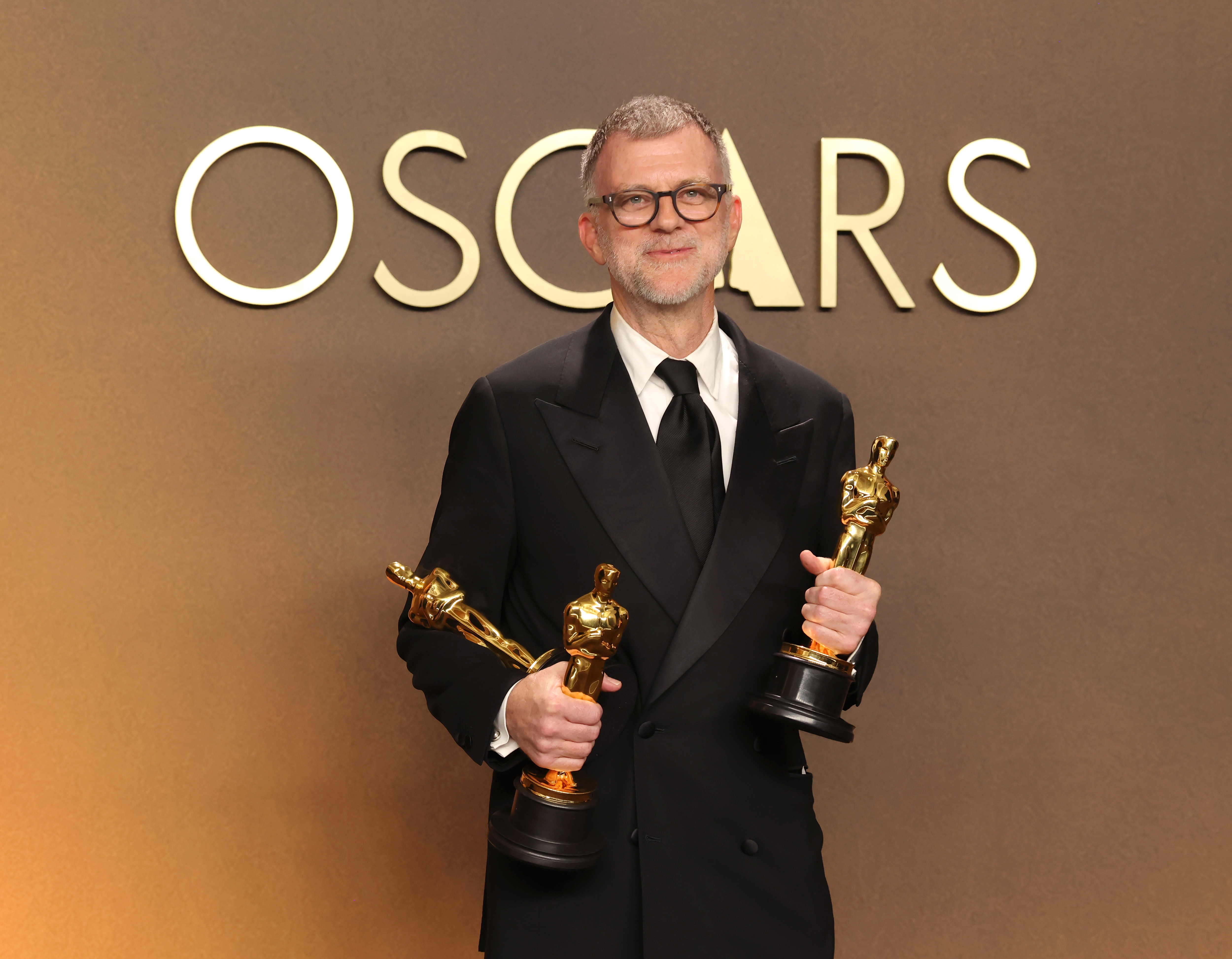 Paul Thomas Anderson holds his Oscars for best adapted screenplay, best director and best picture for <!-- raw HTML omitted -->One Battle After Another<!-- raw HTML omitted -->.
