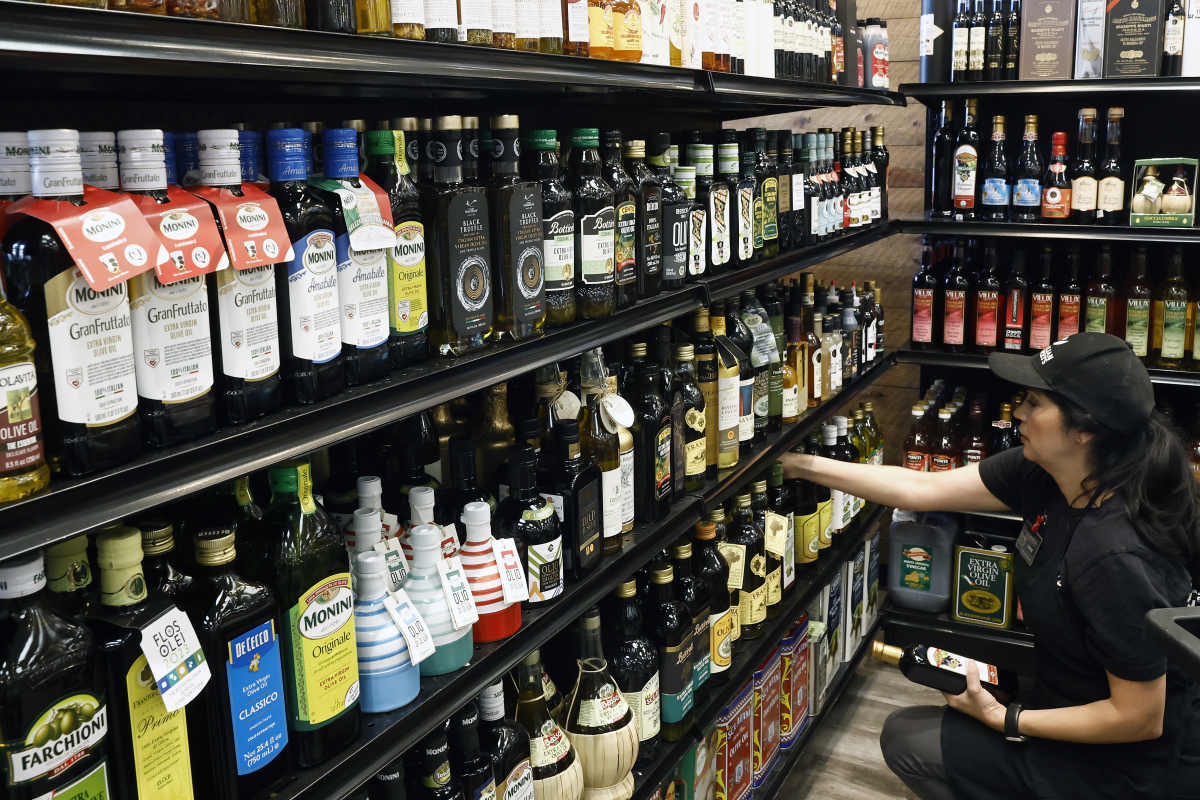 A worker restocks Italian olive oil at Claro's Italian Market in Arcadia, California. Italy exports billions of dollars in food products, including olive oil, and wine to the United States. Now President Trump's new tariffs are adding costs and complications for Italian olive oil producers, including Olio Piro, and their customers.