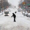 A man carries a shovel as he crosses a street in the Hamilton Heights neighborhood in New York on Sunday.