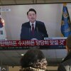 People watch a screen showing South Korean President Yoon Suk Yeol speaking during a televised address at a bus terminal in Seoul on Dec. 12, 2024. 