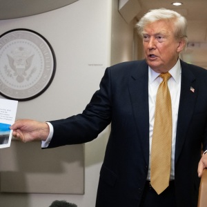 President Donald Trump holds up a copy of his Truth Social post about Air Force One as he speaks with the media aboard Air Force One on July 8, 2026. The president’s media company is offering investors early access to his Truth Social feed for up to $100,000 a month, raising ethical and legal concerns.