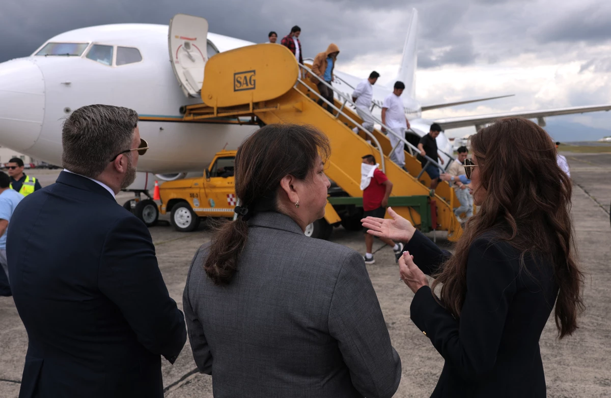 Homeland Security Secretary Kristi Noem (R) talks to ERO Regional Attaché Guadalupe 'Lupita' Serna (C) and U.S. Ambassador to Guatemala Tobin Bradley as people deported from the United States disembark a repatriation flight as Noem is given a tour of Department of Homeland Security operations at La Aurora International Airport on June 26, 2025 in Guatemala City, Guatemala.