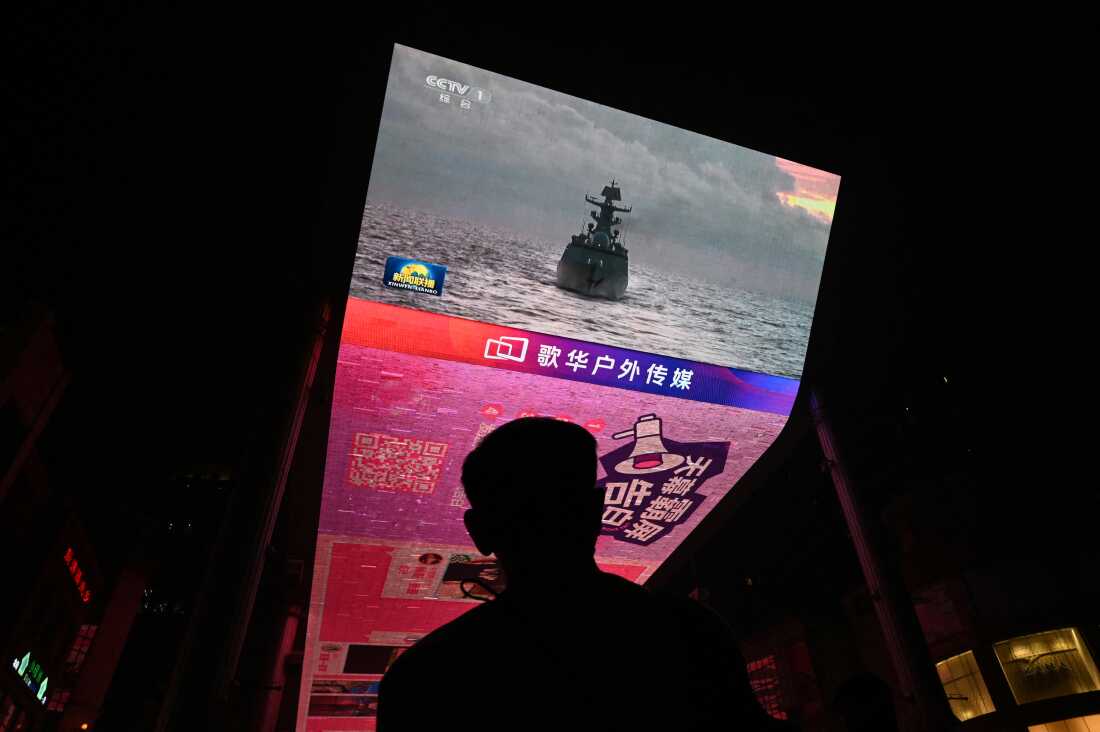 TOPSHOT - A man watches a news programme about Chinese military drills surrounding Taiwan, on a giant screen outside a shopping mall in Beijing on October 14, 2024.