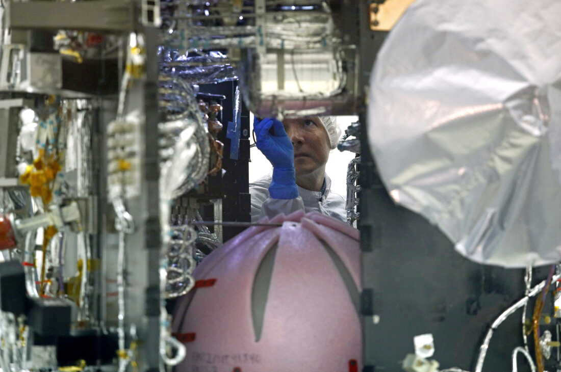 A worker wearing a blue glove looks inside the technically complex interior of the Parker Solar Probe in a clean room at NASA's Goddard Space Flight Center in 2018.