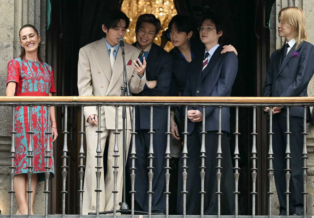 (L-R) Mexico President Claudia Sheinbaum stands with BTS members V, RM, Jung Kook, Suga and Jimin as they greet fans from the balcony of the National Palace at Zócalo Square in Mexico City, May 6, 2026. BTS held three sold-out shows at Estadio GNP Seguros.