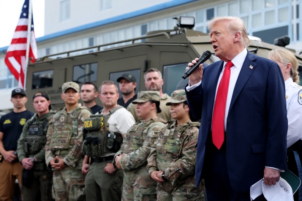 President Trump holds a mic and stands next to National Guard members and federal officers during a visit to the U.S. Park Police Anacostia Operations Facility.