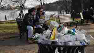 A trash can overflows as people sit outside of the Martin Luther King Jr. Memorial in Washington, D.C.
