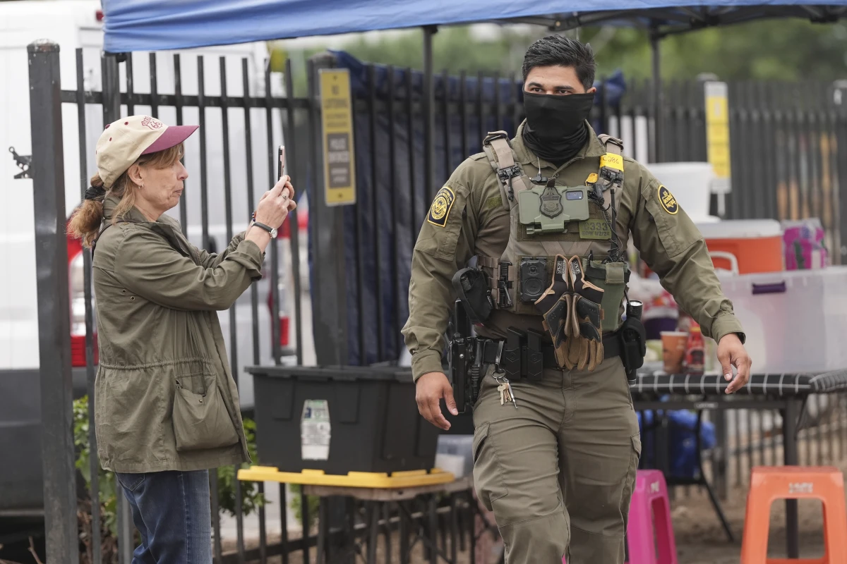 A bystander films an immigration agent during an operation outside a Home Depot in Los Angeles on Aug. 15.
