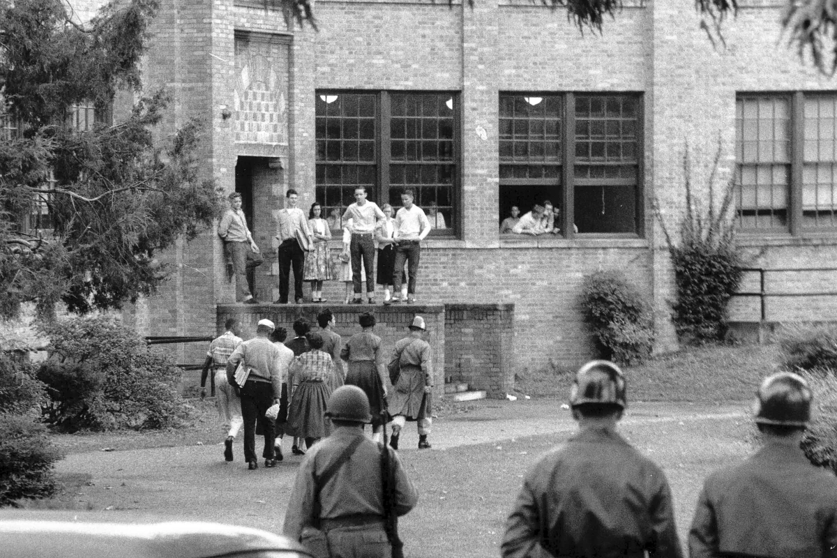 Members of the Little Rock Nine walk onto the campus of Central High School in Little Rock, Ark., with a National Guard member as an escort as other troops watch, on Oct. 15, 1957.