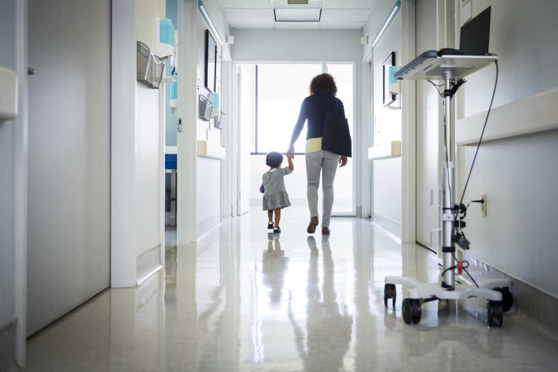 A woman and toddler are shown in a hospital corridor.