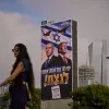 A woman walks past a Likud Party campaign billboard featuring President Trump and Israeli Prime Minister Benjamin Netanyahu, with a Hebrew message reading, "We have one opportunity to win," in Tel Aviv, Israel, on Monday.