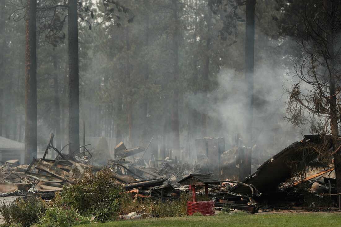 A burned structure smolders due to a wildfire, on Aug. 2, 2026, in Spokane, Wash. (AP Photo/Young Kwak)