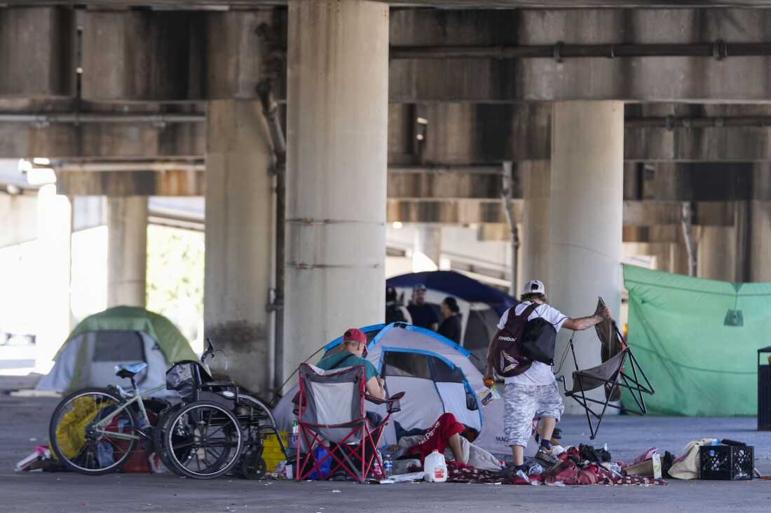 As pessoas que moram em um acampamento sem-teto pegam pertences depois que a polícia do estado da Louisiana deu instruções para que se mudassem para um local pré-designado diferente, enquanto realizam uma varredura antes de um concerto de Taylor Swift em Nova Orleans, quarta-feira, 23 de outubro de 2024.