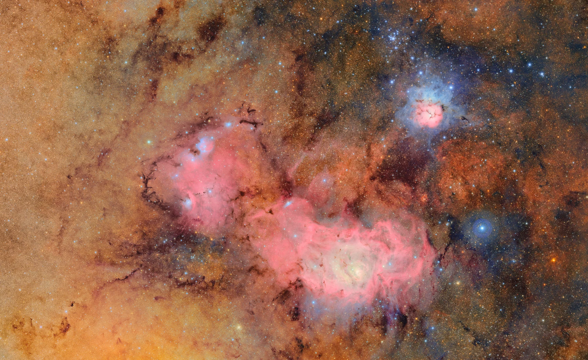 A detailed image of the Trifid nebula and Lagoon nebula, showcasing vibrant clouds of gas and dust against a starry background, captured by the Vera C. Rubin Observatory.