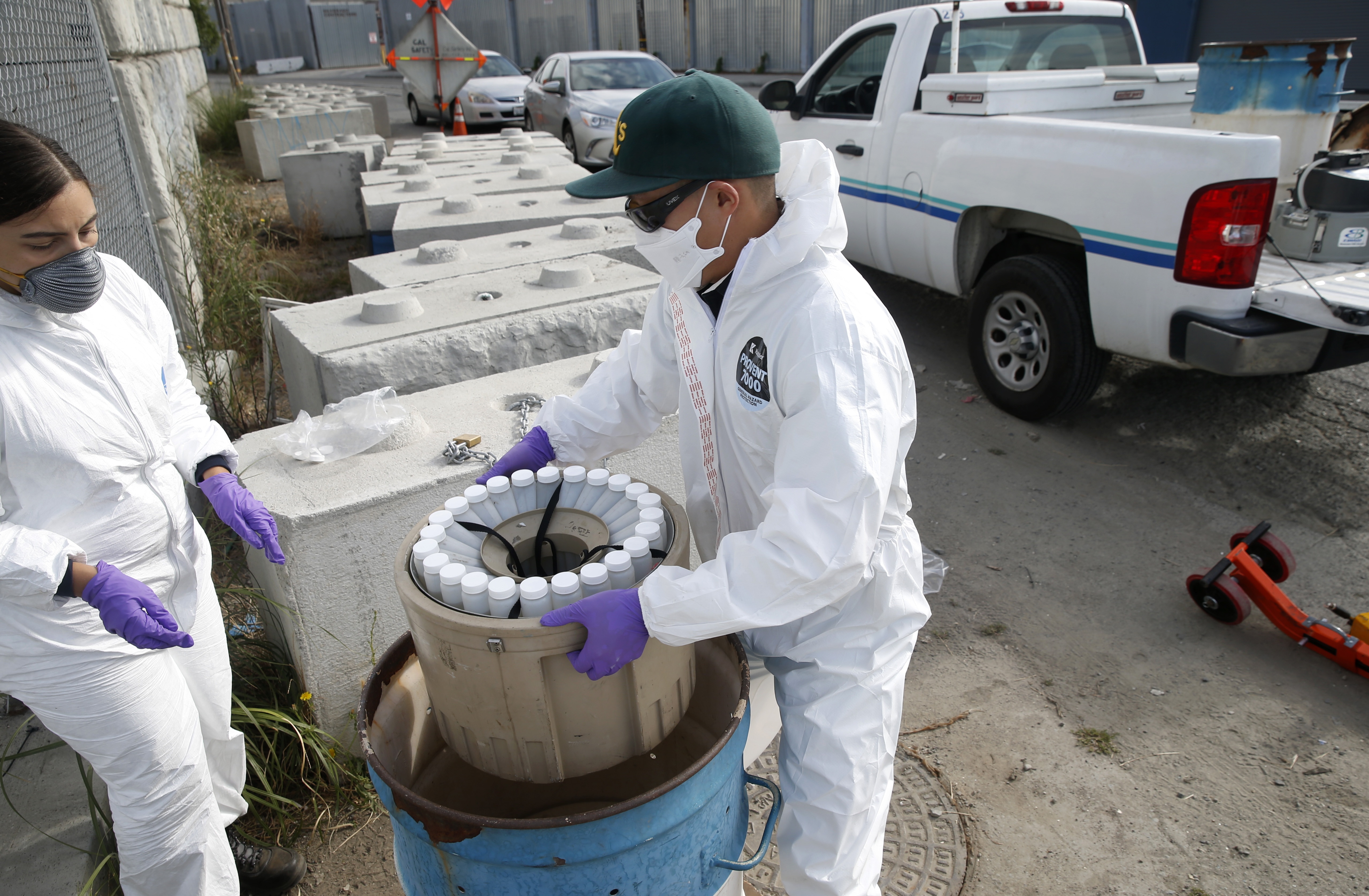 Wastewater sampling plays an increasing role in identifying disease outbreaks. Above: Inspectors in Oakland, Calif., collect samples to send to labs that will try to detect the SARS-CoV-2 virus.