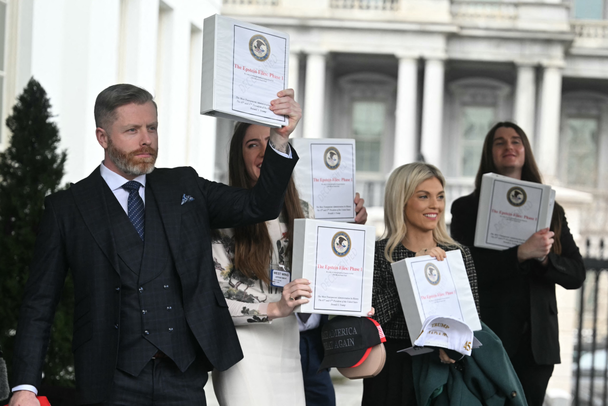 Several conservative commentators carry binders bearing the seal of the Justice Department reading 'The Epstein Files: Phase 1' as they walk out of the West Wing of the White House in on Feb. 27.