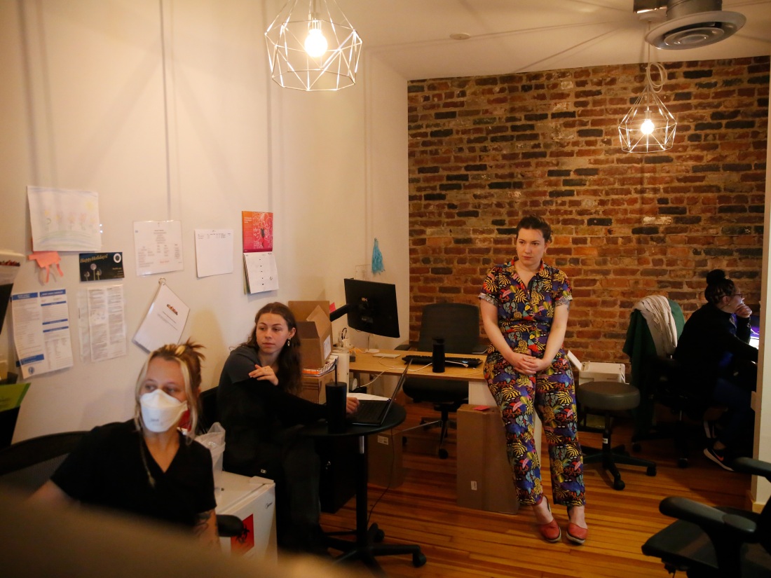 Dr. Stephanie Arnold, a primary care physician, meets with her staff at Seven Hill Family Medicine in Richmond, Va. to discuss the schedule for the day. The room has warm lighting and brick walls.