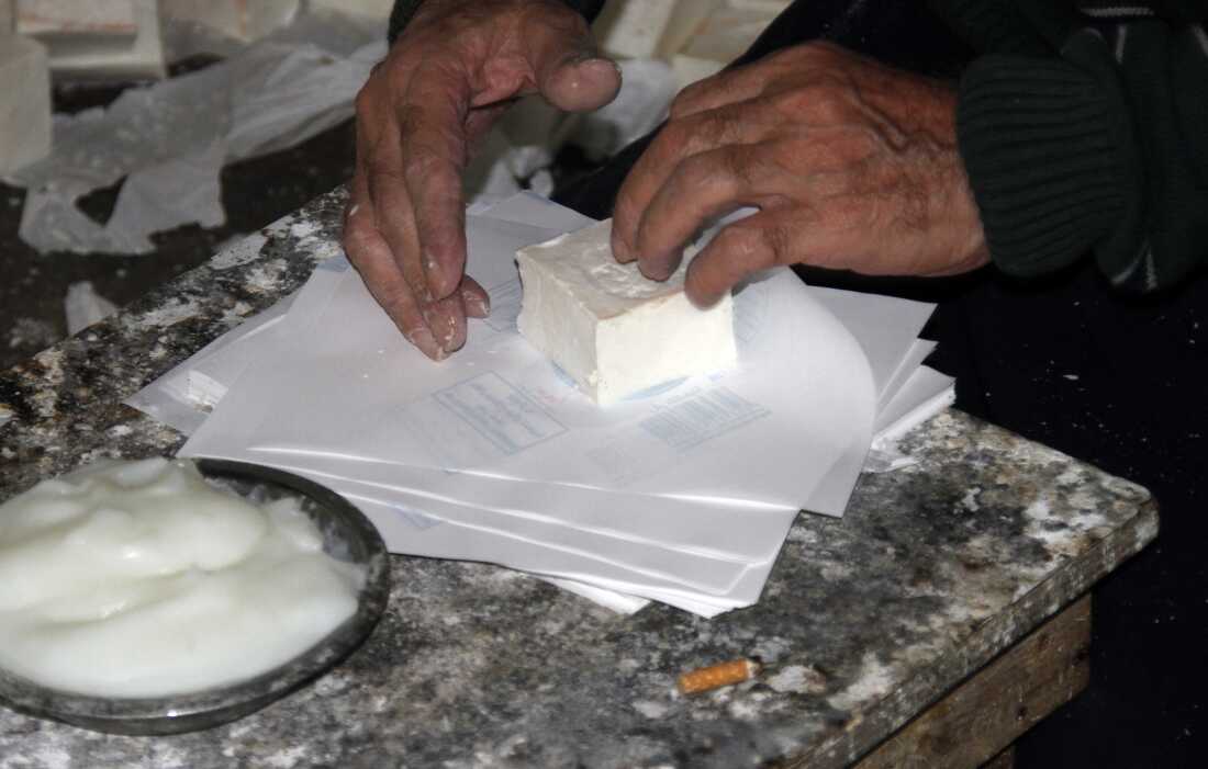 A worker wraps a soap bar by hand in the company’s signature white paper packaging.