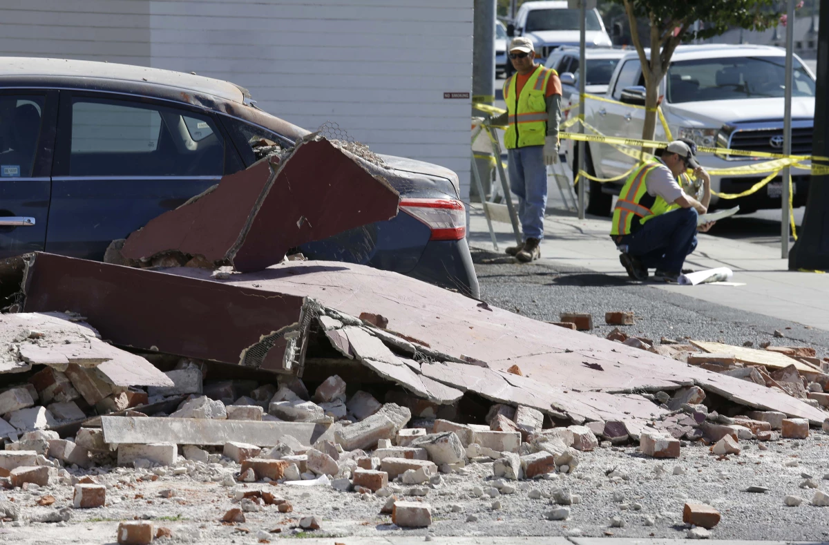 City workers at right map out the installation of fencing around earthquake damaged buildings Tuesday, Aug. 26, 2014, in Napa, Calif.