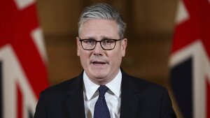 This photo shows British Prime Minister Keir Starmer as he delivers a statement. He's wearing a suit and tie, and behind him are two U.K. flags.
