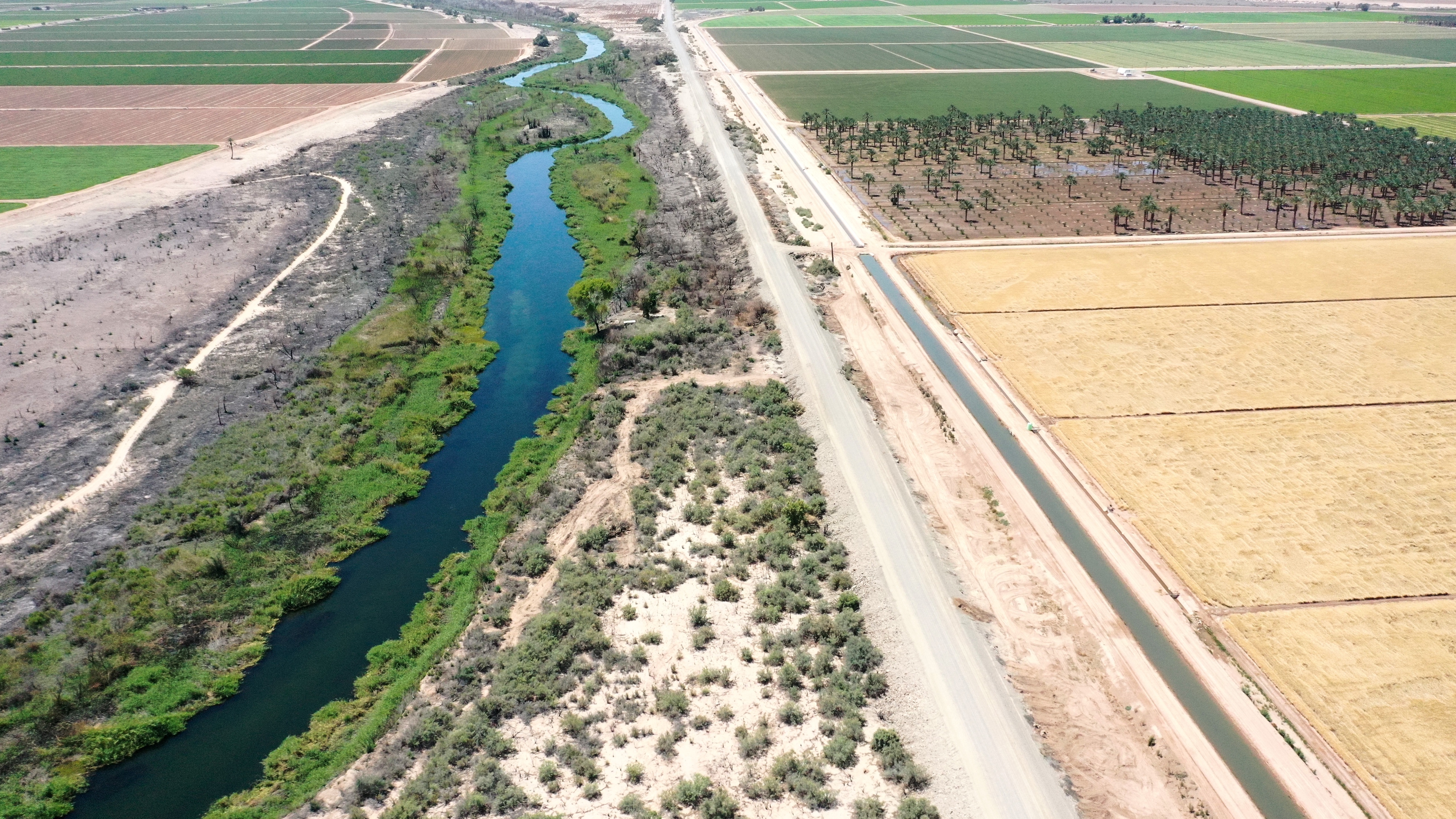 An aerial view shows the long-depleted Colorado River (L) as it flows between California (R) and Arizona, and an irrigation ditch (R) carrying river water toward Quechan tribal land on May 26, 2023 near Winterhaven, California.