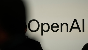 A person in silhouette stands in front of a screen showing OpenAI's logo.