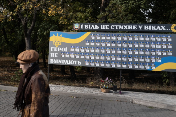 DOBROPILLYA, UKRAINE - OCTOBER 17, 2024 A woman passes a monument to fallen Ukrainian soldiers in Dobropillya, Ukraine on Thursday, October 17, 2024. Like the nearby coal mining center of Pokrovsk, Dobropillya frequently comes under aerial attack from Russian missiles and drones. Ukrainians are worried about the upcoming US election and fear that a Donald Trump victory could turn off the flow of financial and military aid. (Photo by Michael Robinson Chávez for National Public Radio)