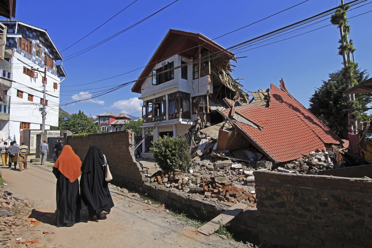 Women walk past a damaged house in Bandipora, India, on April 27. Following the April 22 attack that killed at least 26 people, India ordered Pakistani nationals to leave the country and Indian security forces demolished houses linked to active militants across Kashmir, according to officials.