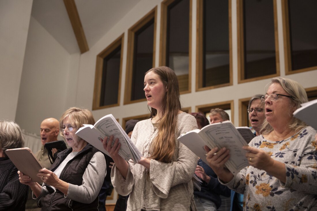 Choir members sing with songbooks in hand.
