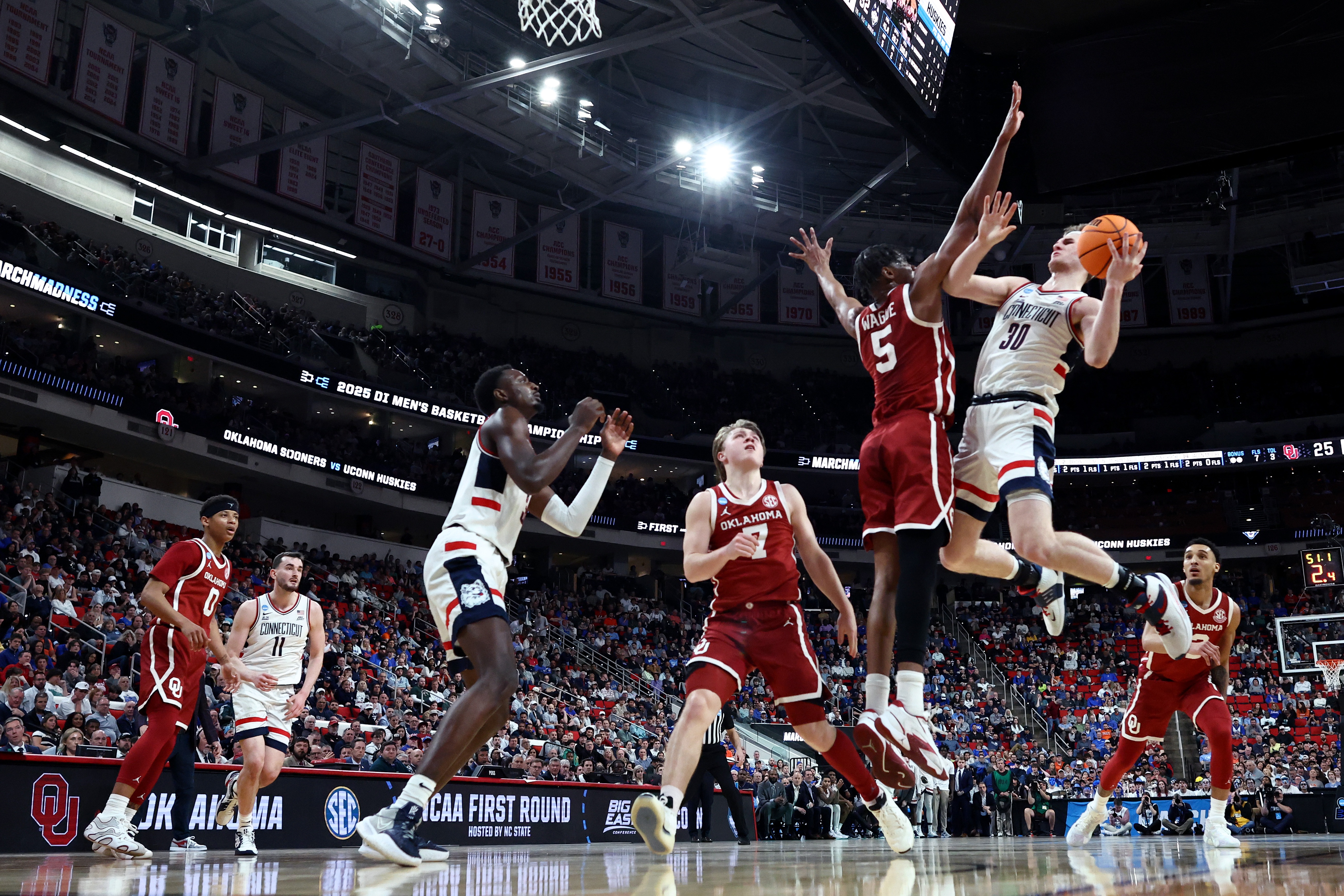 Liam McNeeley #30 of the Connecticut Huskies shoots the ball while defended by Mohamed Wague #5 of the Oklahoma Sooners during the first half in the first round of the NCAA Men