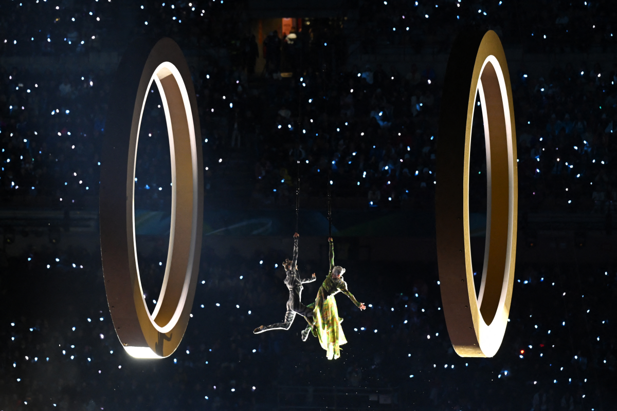 Two performers are suspended between two large rings.