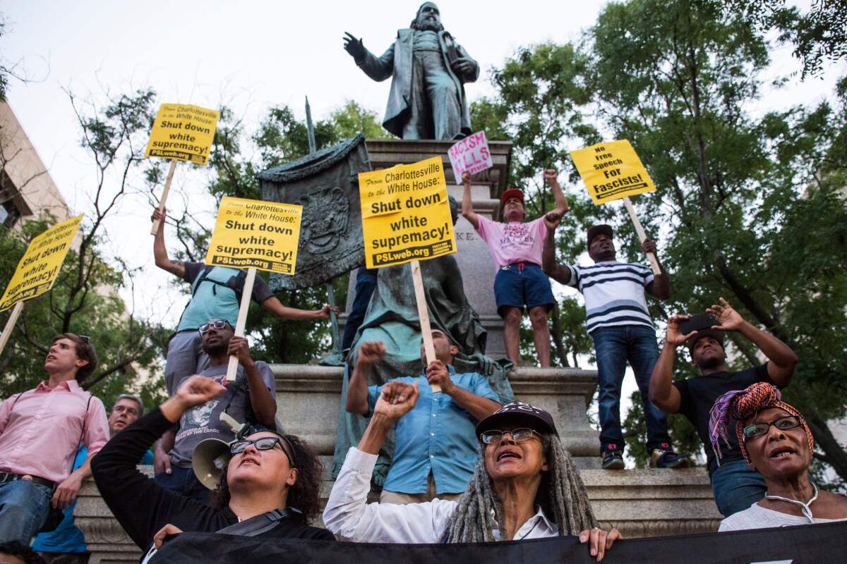 Demonstrators hold signs in front of the statue of Confederate General Albert Pike on Aug. 13, 2017, in Washington, DC., during a vigil in response to the death of a counter-protestor in the 'Unite the Right' rally in Charlottesville, Va.