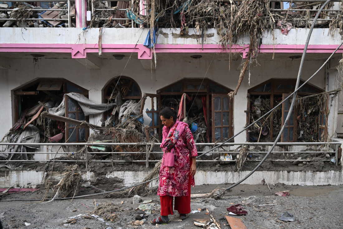 A woman salvages usable materials from her house deluged in sludge following flash floods at Devighat in Nepal's Nuwakot district.