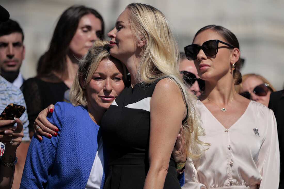 Survivor Anouska De Georgiou embraces survivor Danielle Bensky as survivor Marina Lacerda looks on during the news conference.