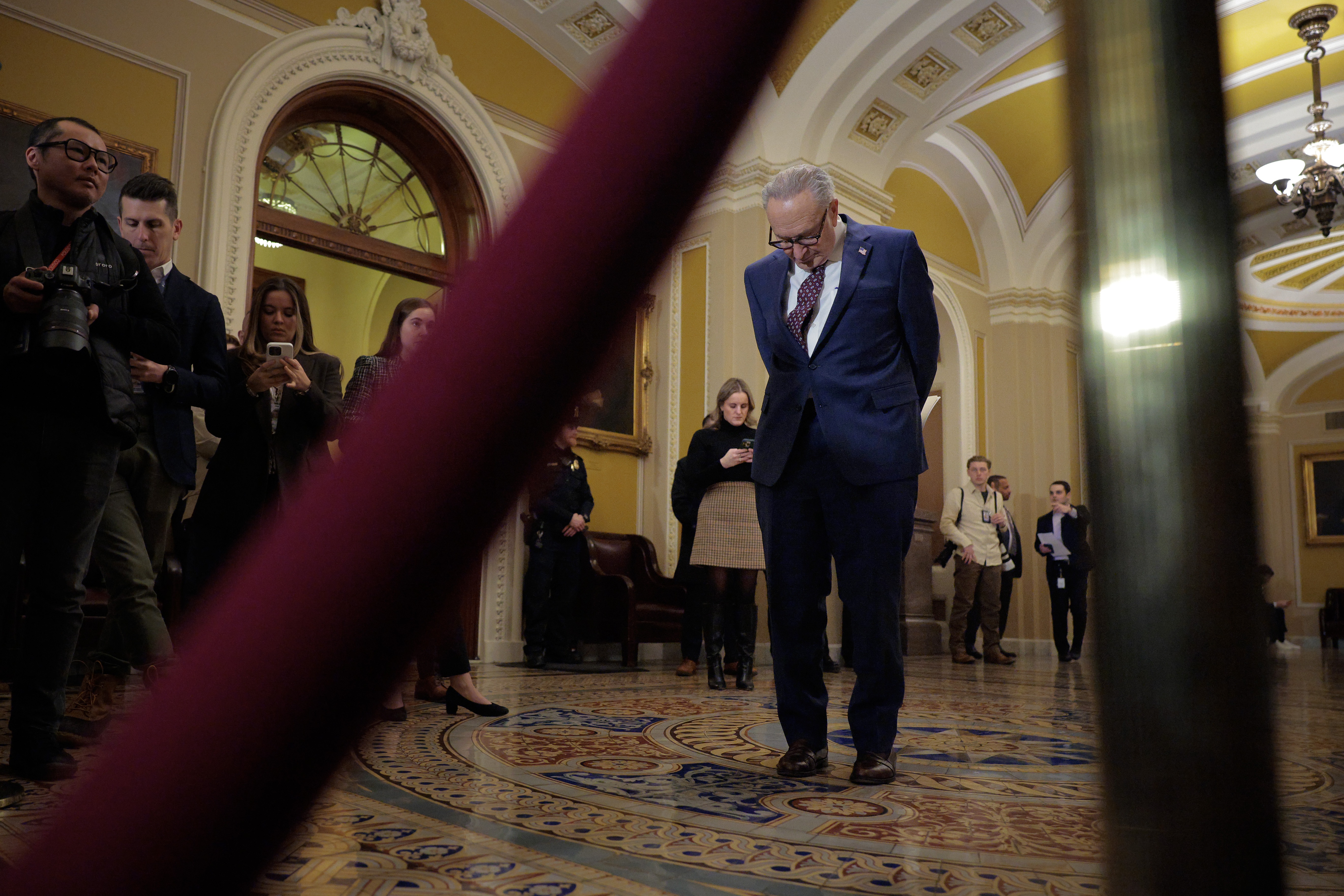 Senate Minority Leader Charles Schumer, D-N.Y., stands back as fellow Democrats talk to reporters at the U.S. Capitol on Wednesday.