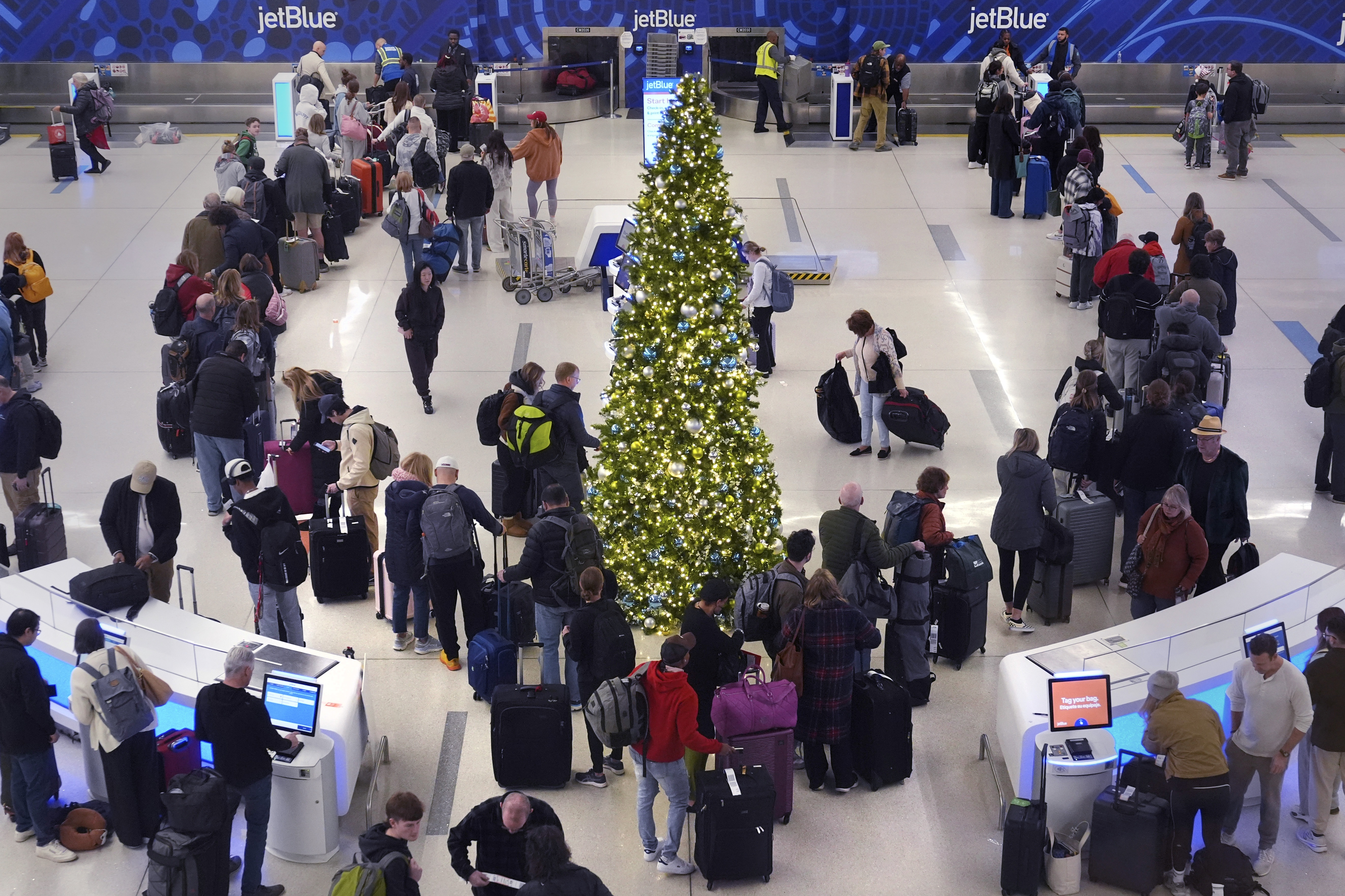 Holiday travelers wait in line to check their bags at the JetBlue terminal at Boston
