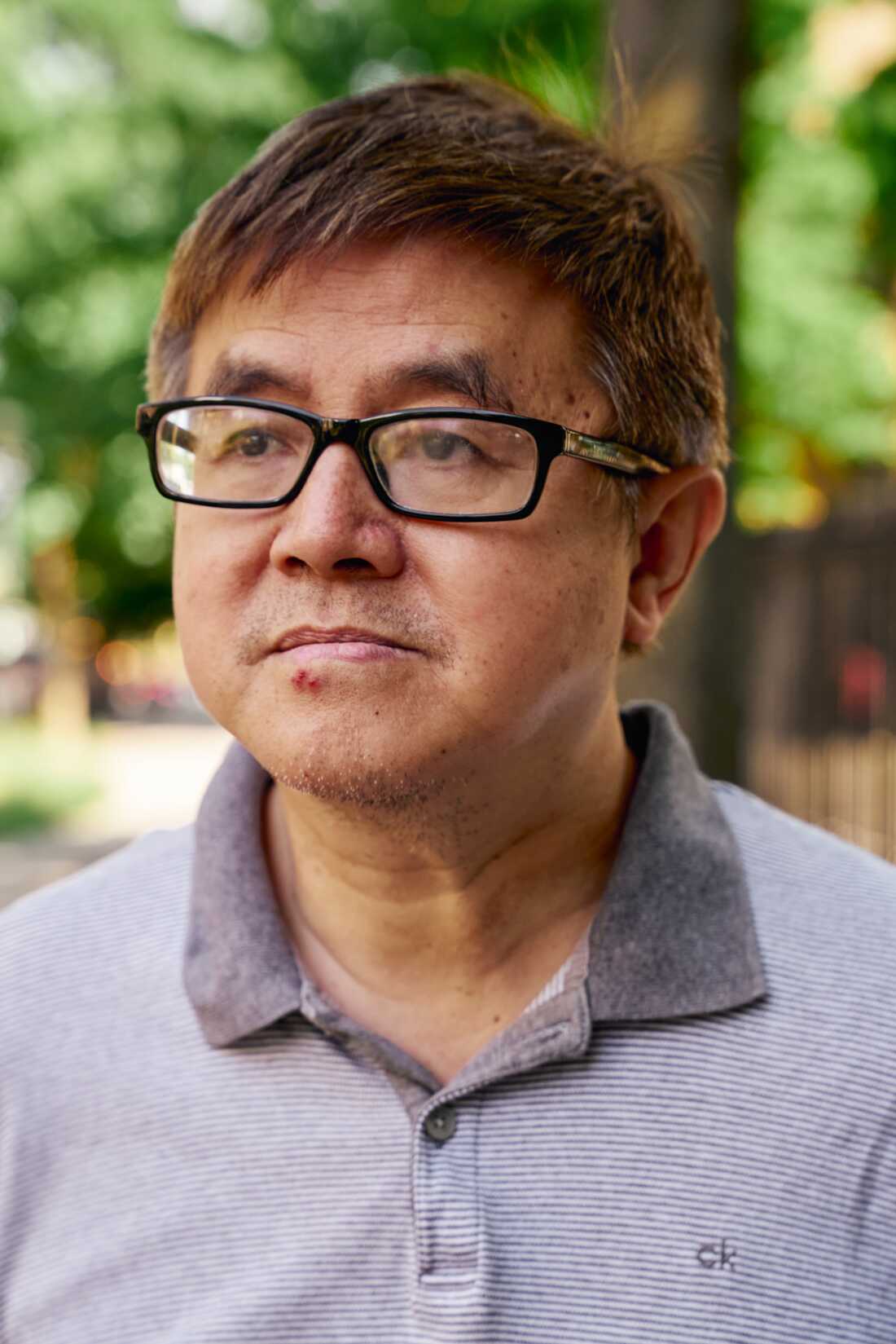 A man wearing glasses and a gray collared shirt.