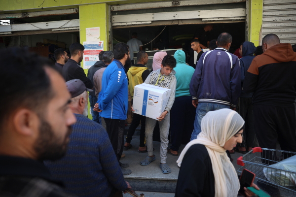 People queue to receive humanitarian aid, supplied by the World Food Program, in the Bureij refugee camp in the central Gaza Strip on November 18, 2024.